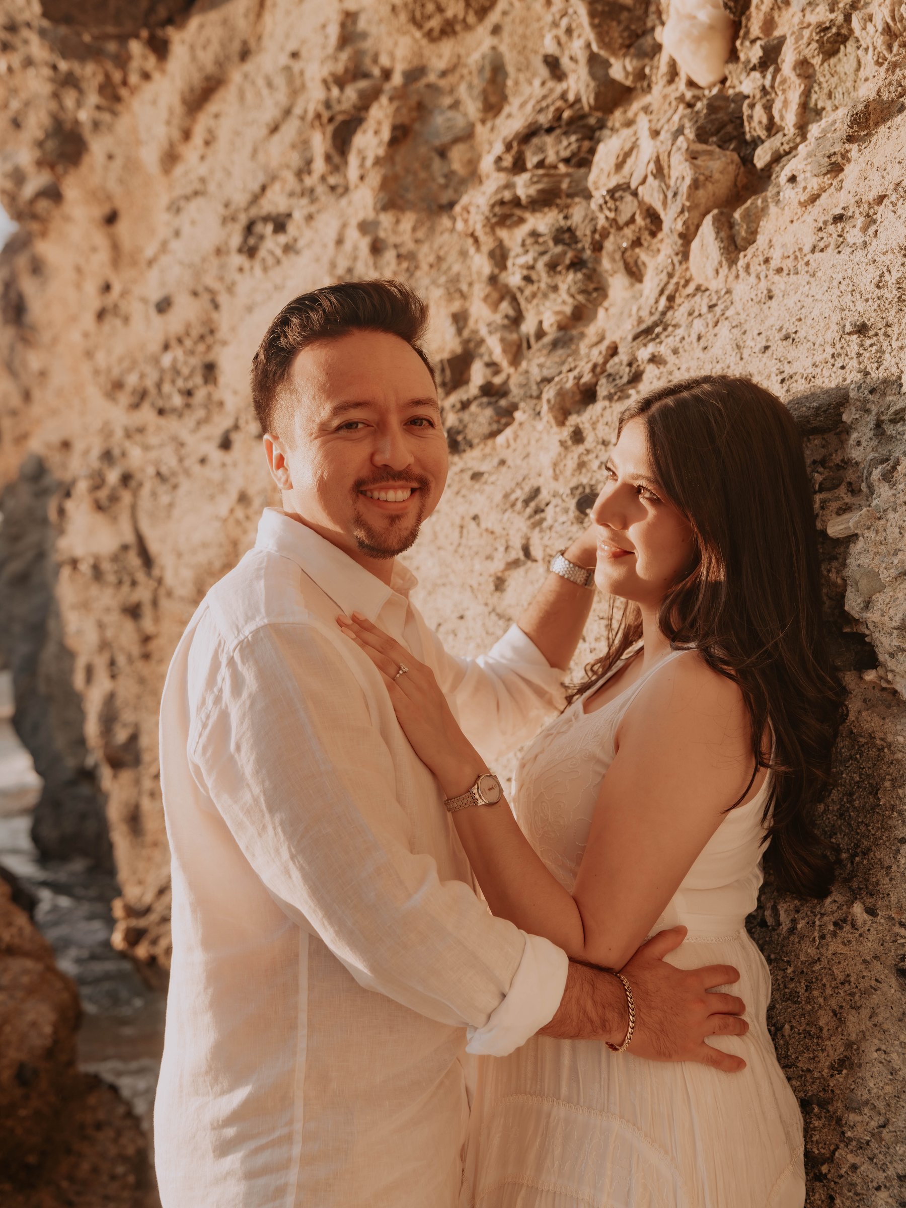Guadalupe and Harrison embracing under a rock archway, smiling at the camera