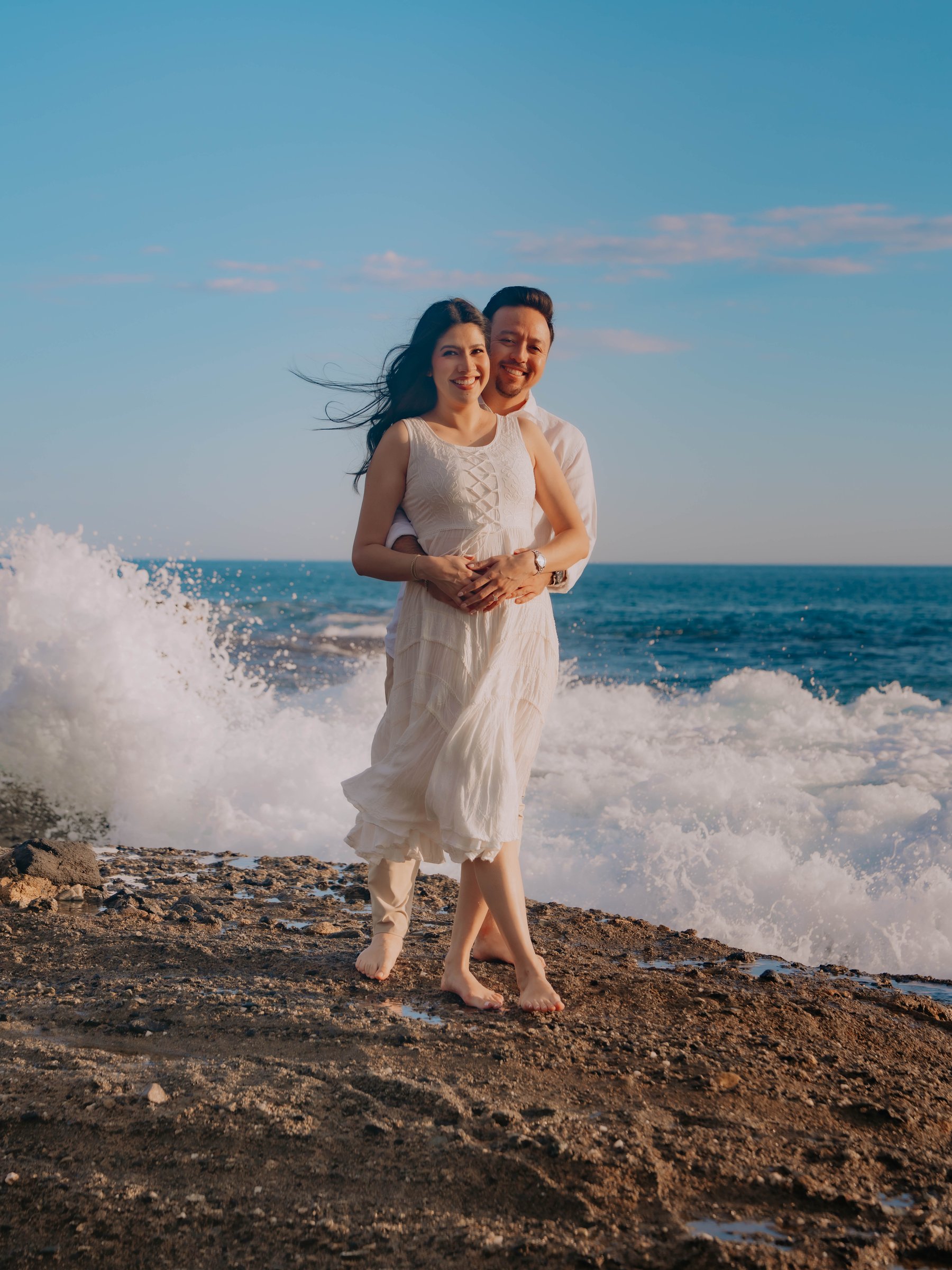 Guadalupe and Harrison standing together inside a rock archway on the beach
