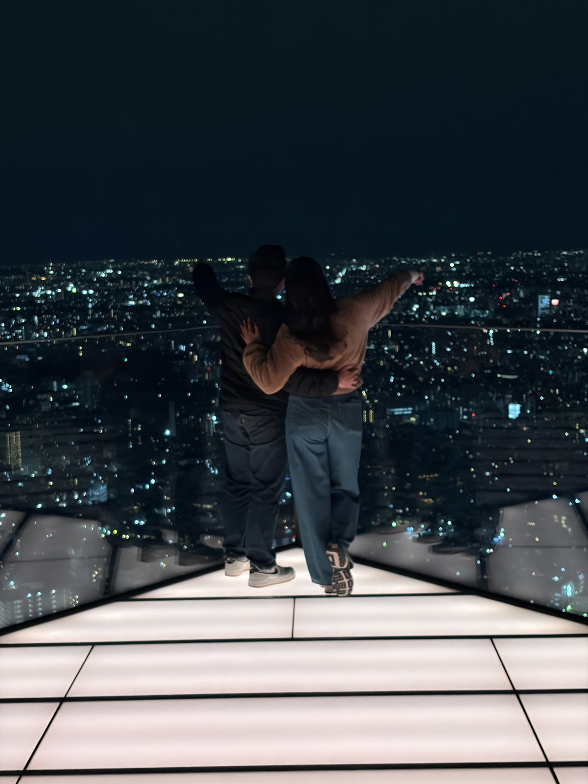Guadalupe and Harrison taking in the night skyline from an observation deck in Tokyo