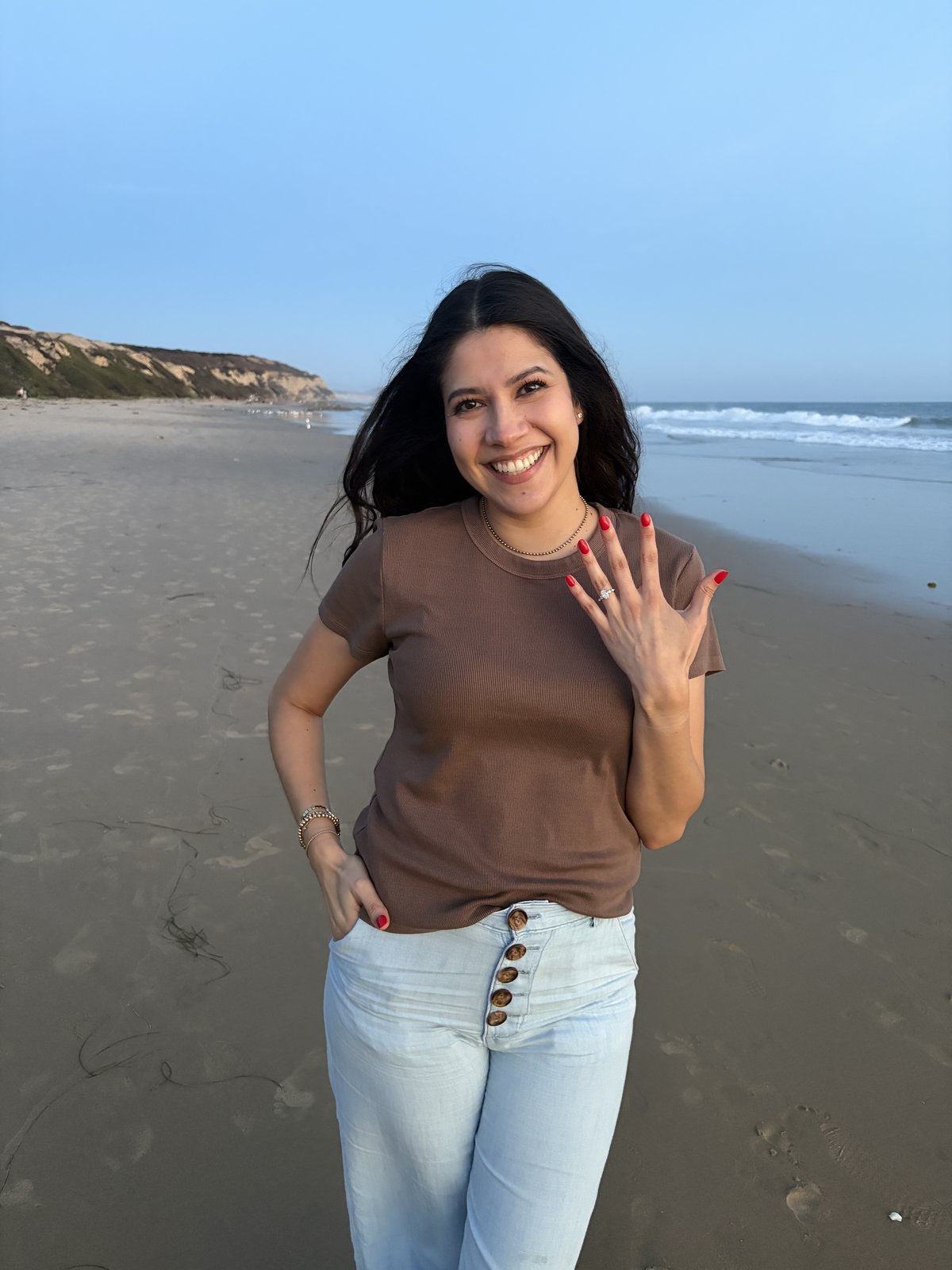 Harrison kneeling on the beach as he proposes to Guadalupe